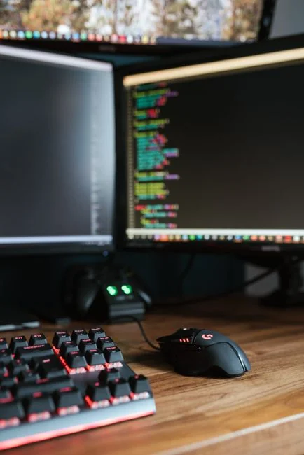 Close-up of hands typing on a laptop next to a cup of coffee on a wooden desk.